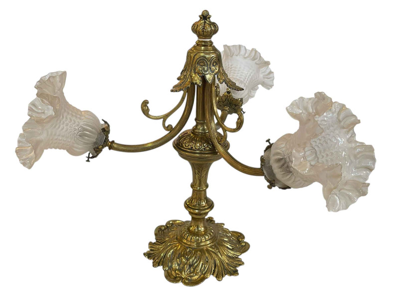 Ornate brass three branch table lamp with glass shades.