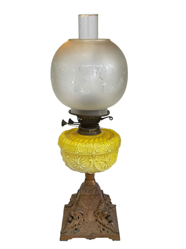 Victorian cast base oil lamp with yellow glass reservoir and frosted and etched glass shade.