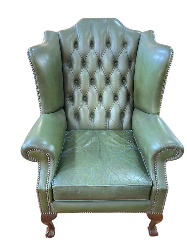 Green deep buttoned leather and studded wing back armchair on ball and claw legs.