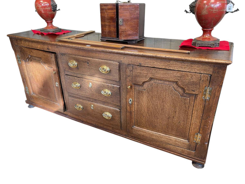 Georgian oak dresser having three central drawers flanked by two arched fielded panel doors, 77cm by 182cm by 50cm.