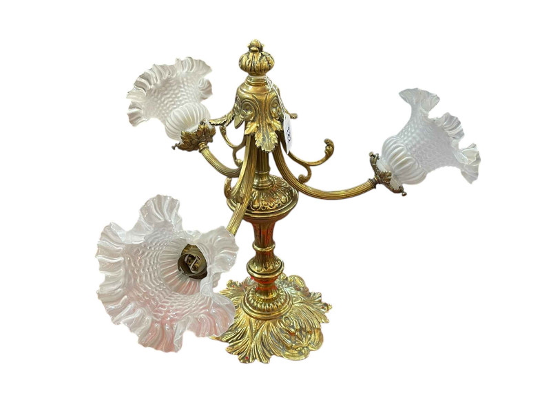 Ornate brass three branch table lamp with glass shades.