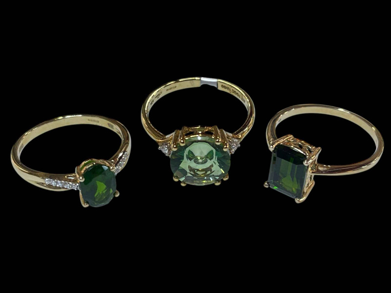 Three 9 carat gold and green gem set dress rings.