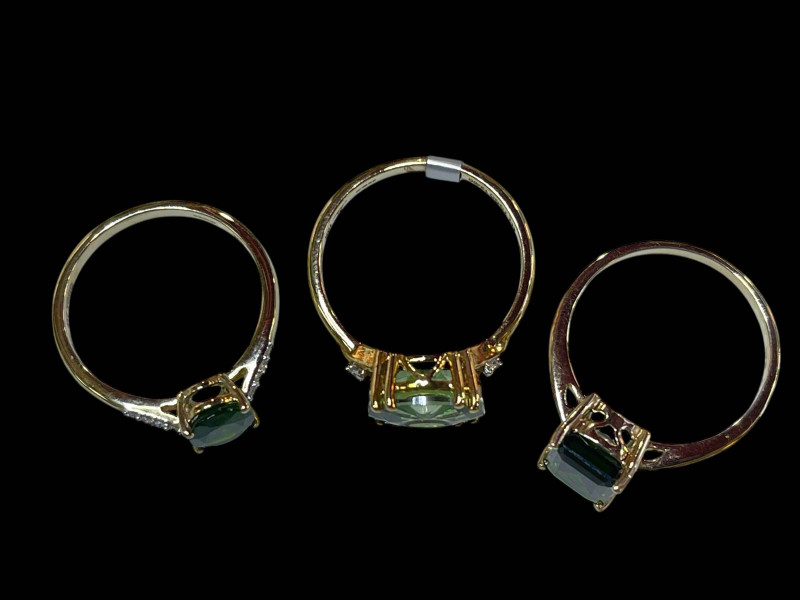 Three 9 carat gold and green gem set dress rings.