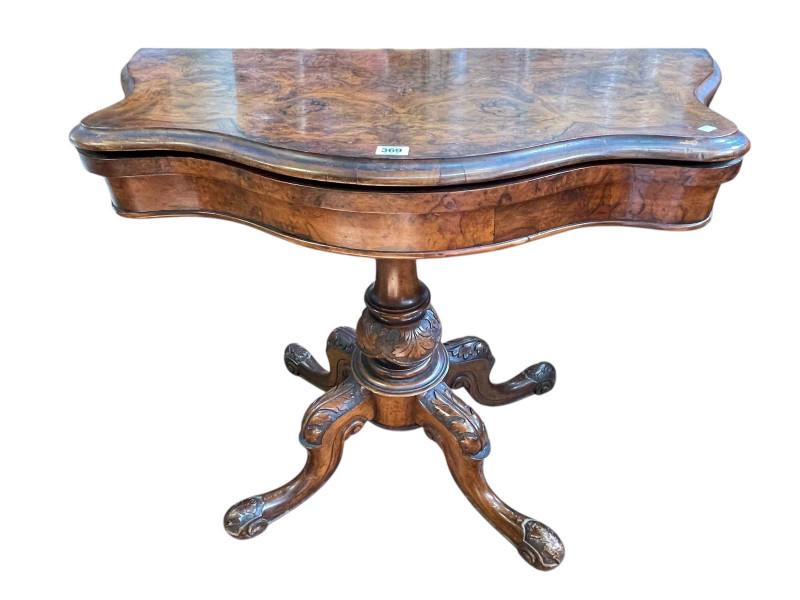 Victorian figured walnut fold top card table of serpentine form on carved pedestal to four scrolled legs.