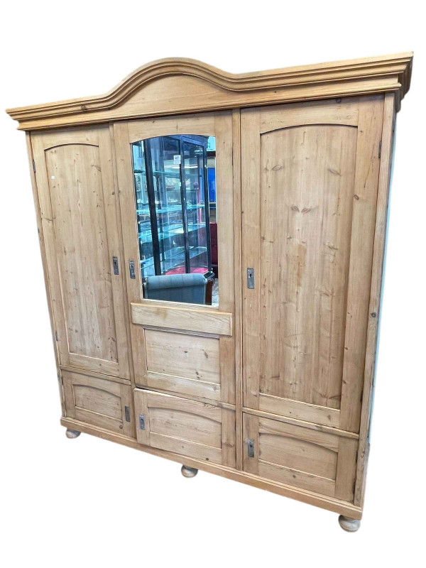 Continental pine arched top wardrobe having three doors, one with mirror panel, above three small doors on bun feet, 203cm by 184cm by 54cm.
