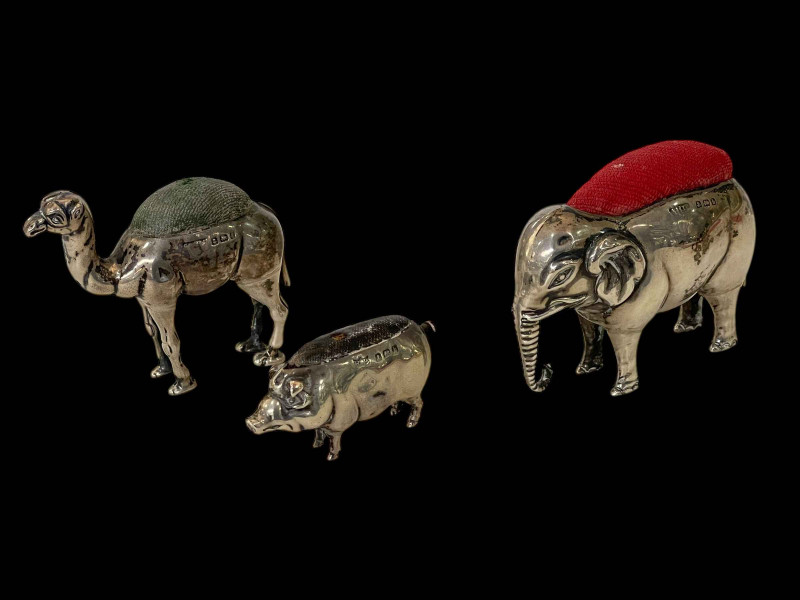 Three Edwardian silver pin cushions, Elephant with makers mark A & C Co, Birmingham 1907, 5cm high, Camel, Birmingham 1906, 5cm high and Pig, Birmingham 1907.