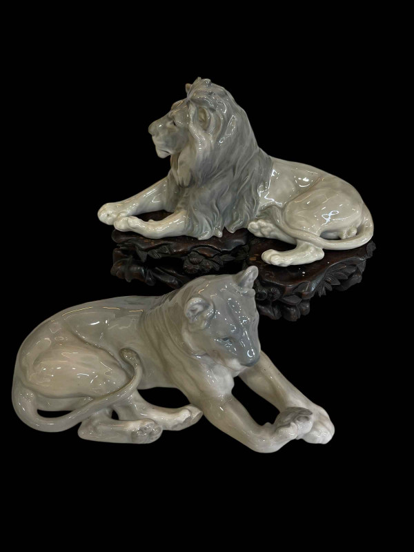 Bing & Grondahl figurine of Resting Lion designed by Lauritz Jensen, model No 1793, and Royal Copenhagen figurine of Resting Lioness designed by Lauritz Jensen model No 804, with Chinese wood stand.