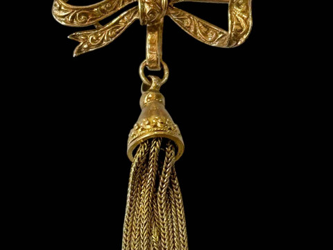 Gold chased ribbon and tassel brooch, 3cm across.