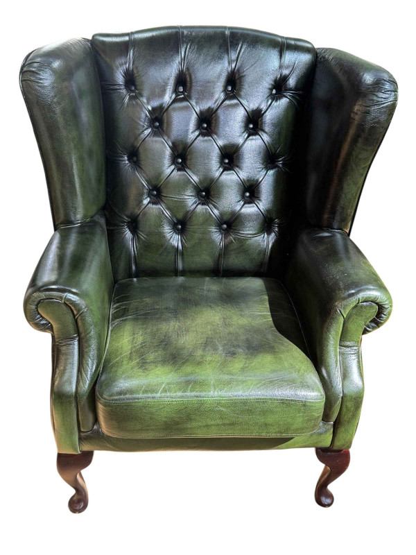 Green button backed leather wing armchair.