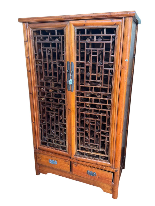 Oriental style wine cabinet having two fretwork panel doors enclosing a ninety one bottle compartment above two drawers, 173cm by 103cm by 58cm.