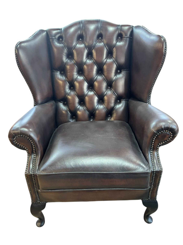 Brown buttoned backed leather and studded wing armchair.