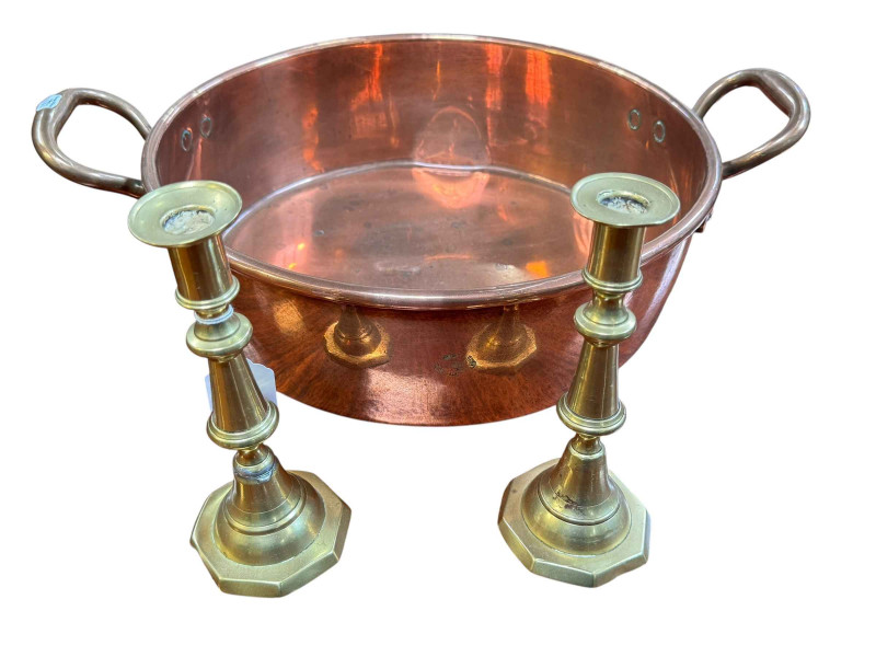 Polished copper two handled pan and a pair of brass candlesticks.