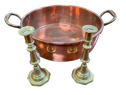Polished copper two handled pan and a pair of brass candlesticks.