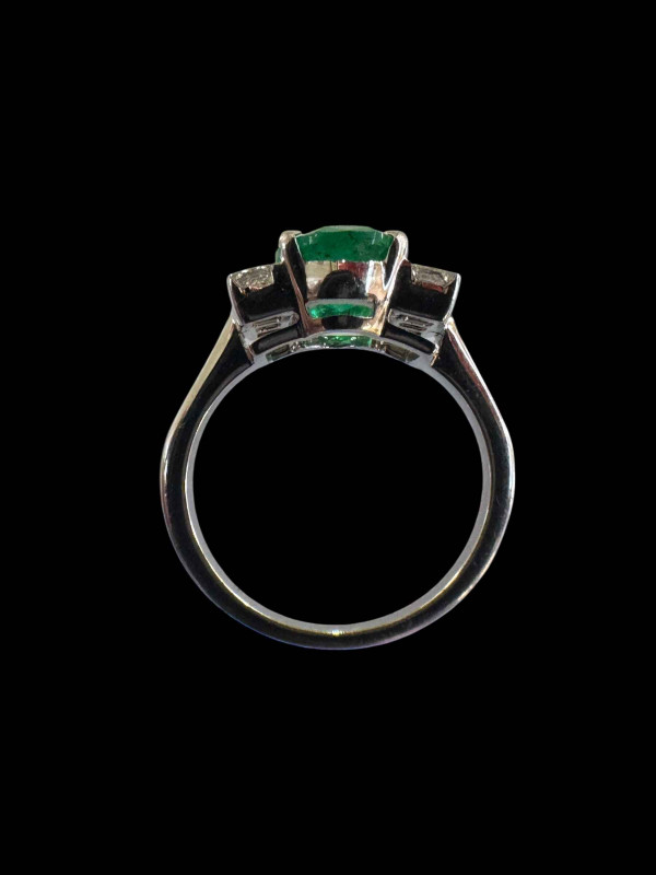 Emerald and diamond ring set in 18 carat white gold, the oval emerald 4.5 carats flanked by three princess cut diamonds to each shoulder, totalling 0.5 carats, size N.