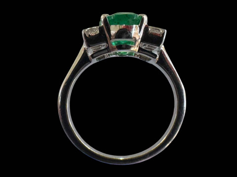 Emerald and diamond ring set in 18 carat white gold, the oval emerald 4.5 carats flanked by three princess cut diamonds to each shoulder, totalling 0.5 carats, size N. thumbnail