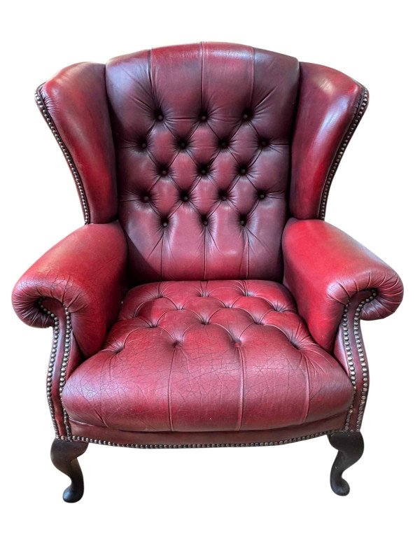 Red deep buttoned leather and brass studded wing back armchair.