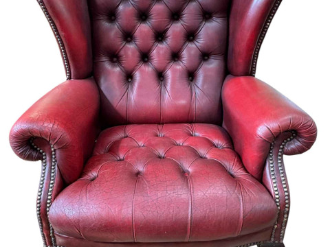 Red deep buttoned leather and brass studded wing back armchair.