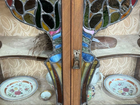 Art Nouveau mahogany cabinet, the canopied top having central glazed panel door flanked by two shaped shelves above two coloured leaded glass panel doors, 183.5cm by 138cm by 46cm. thumbnail