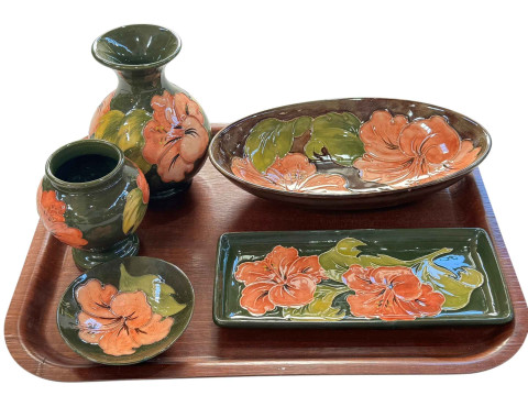 Five pieces of Moorcroft Pottery decorated with hibiscus, two vases, oval...
