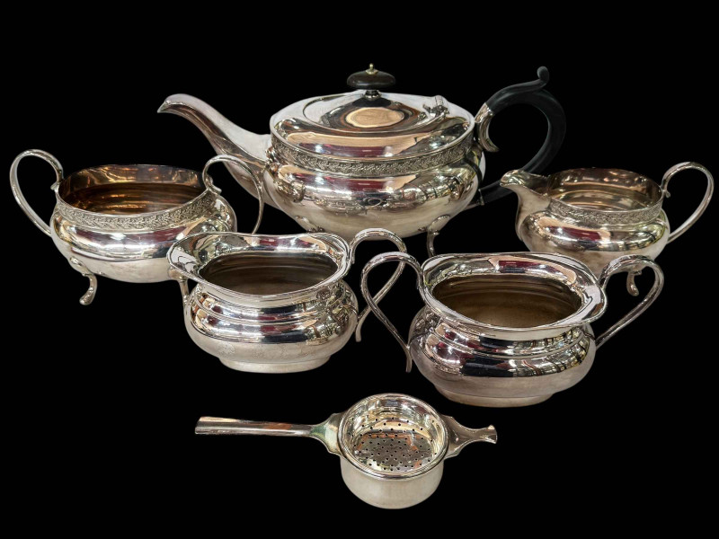 Silver plated tea set with oak leaf border, sugar and cream, and tea strainer.