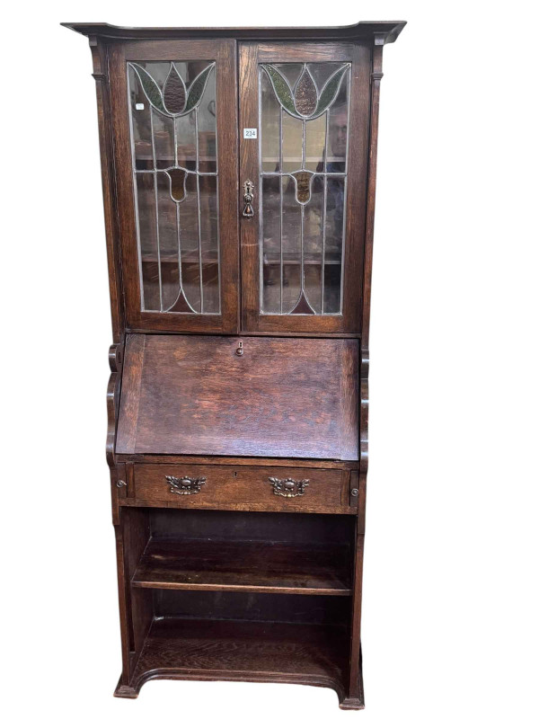 Art Nouveau oak bureau bookcase having two leaded glazed doors above a fall front with a drawer and shelf below, 181cm by 77cm by 38cm.
