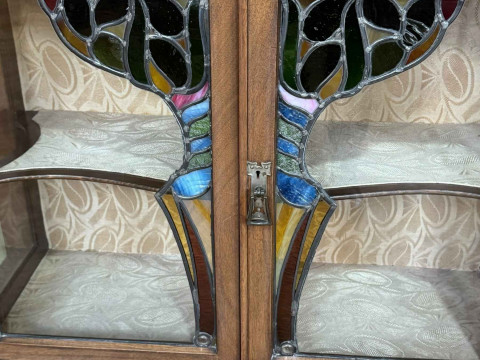 Art Nouveau mahogany cabinet, the canopied top having central glazed panel door flanked by two shaped shelves above two coloured leaded glass panel doors, 183.5cm by 138cm by 46cm. thumbnail