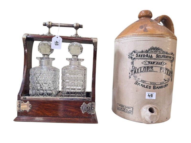 Oak and white metal bound two bottle tantalus and a Brailes Banbury stoneware bottle.