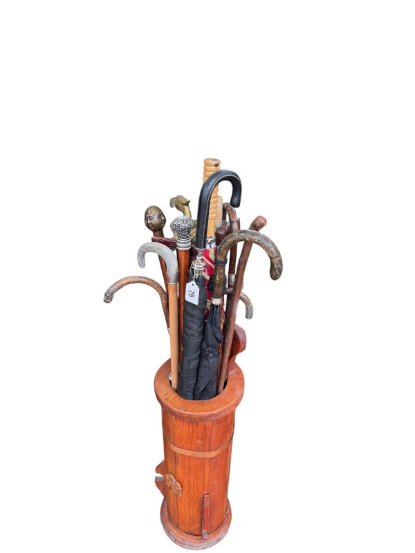 Collection of walking sticks, umbrellas, glass twist canes housing in a stick stand.