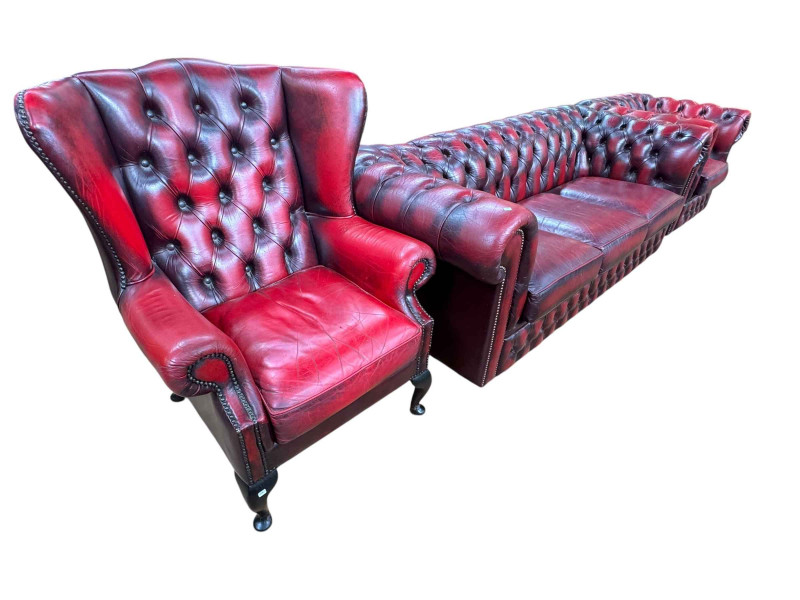 Ox blood buttoned leather three piece Chesterfield suite comprising three seater settee, wing armchair and club armchair.