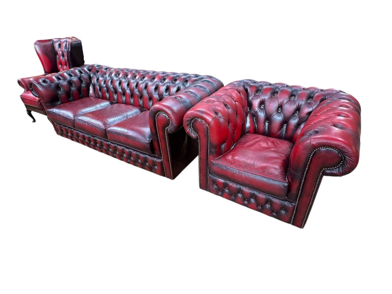 Ox blood buttoned leather three piece Chesterfield suite comprising three seater settee, wing armchair and club armchair.