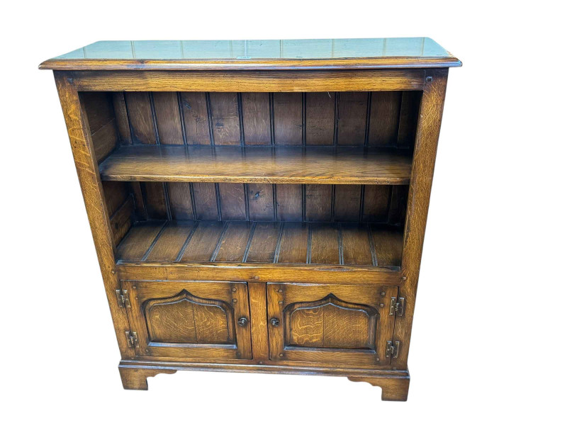 Titchmarsh and Goodwin oak bookcase, the open top having a fixed shelf above two fielded arched panel doors, 106cm by 95cm by 31cm.