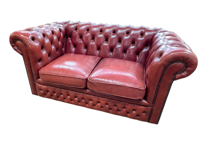 Red deep buttoned leather two seater Chesterfield, 75cm by 154cm by 90cm.