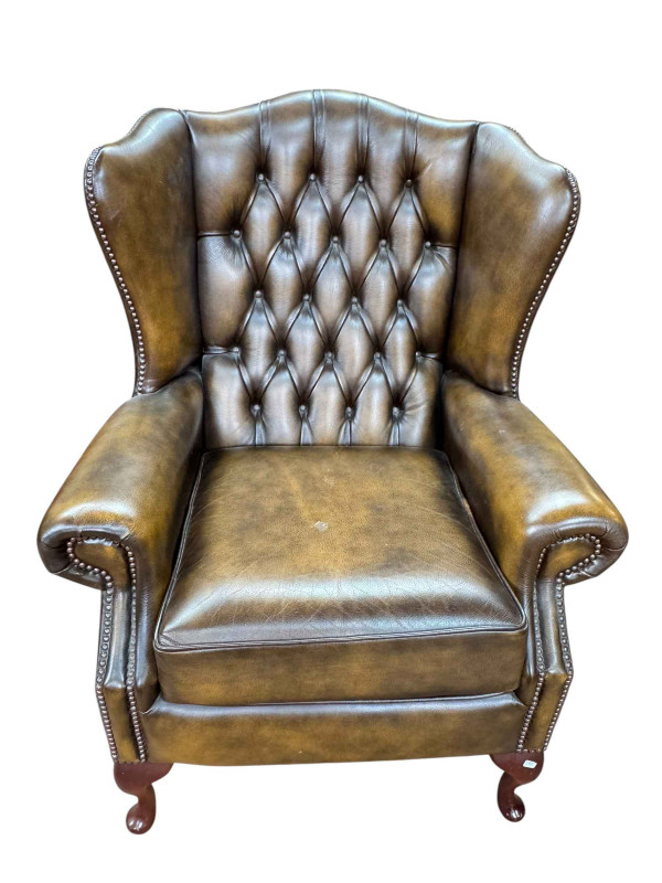 Brown leather button backed and studded wing armchair, 108cm by 82cm.