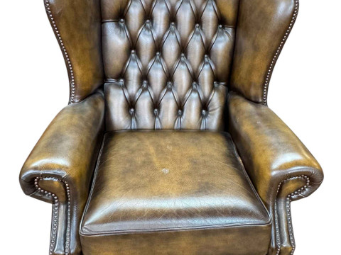 Brown leather button backed and studded wing armchair, 108cm by 82cm.
