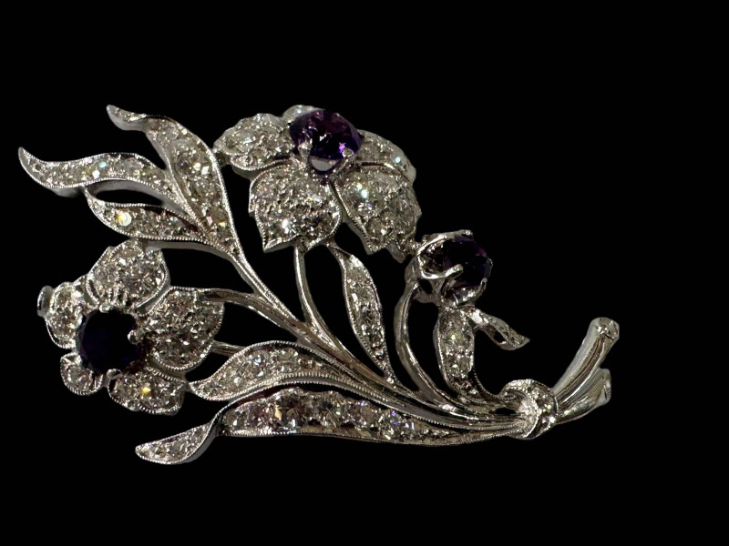 Amethyst and diamond white gold floral brooch, well constructed and having three amethyst with total weight approximately 1.8 carat, and seventy three diamonds with total weight in excess of three carat, tested for 18 carat white gold certified by valuation in 2011, 5.75cm.