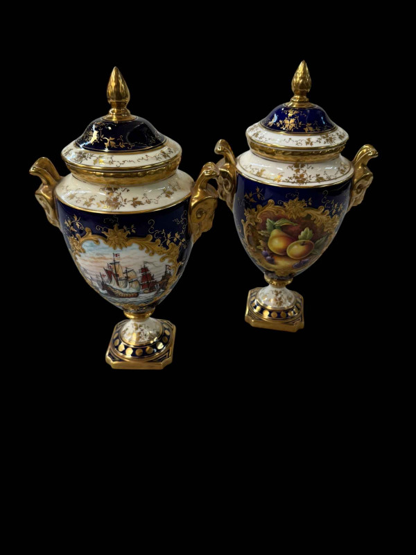 Two Coalport urn vases with covers, one painted by Malcolm Harnet with Spanish Armada, the other with fruit still life by D Millor, 24cm.