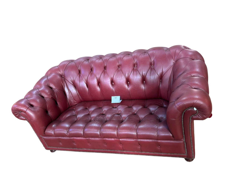 Cherry red all buttoned leather and studded two seater Chesterfield settee, 77cm by 182cm by 90cm.