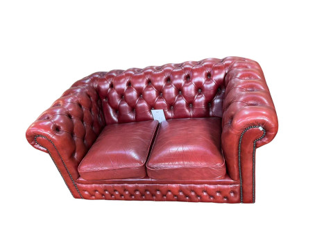 Red deep buttoned leather two seater Chesterfield, 75cm by 154cm by 90cm.