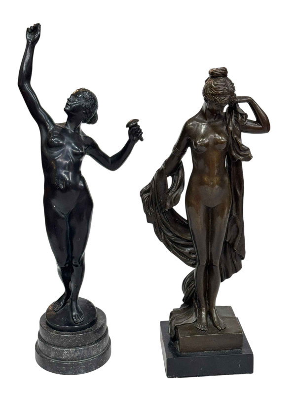 Two nude lady figures in pose on marble plinths.