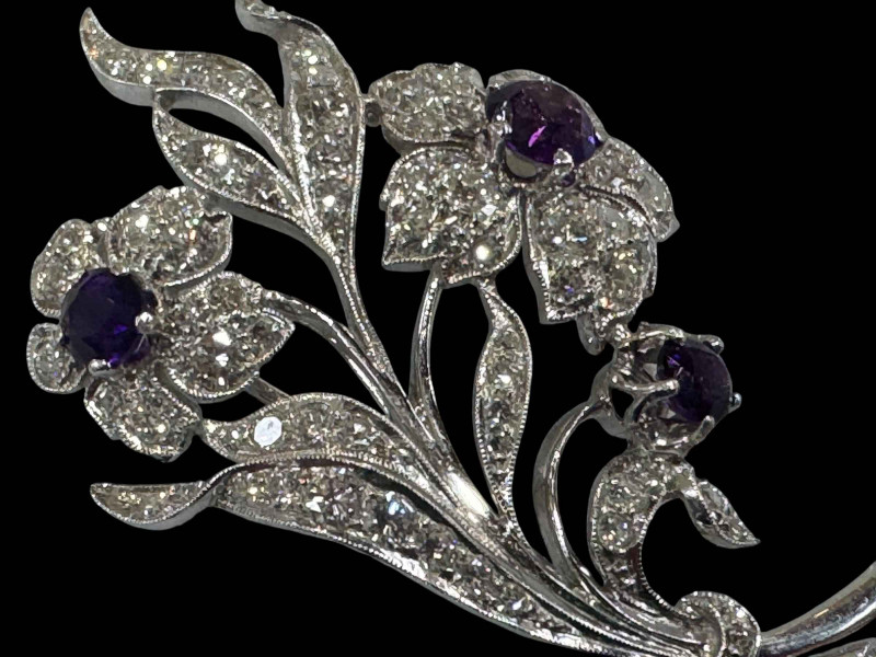 Amethyst and diamond white gold floral brooch, well constructed and having three amethyst with total weight approximately 1.8 carat, and seventy three diamonds with total weight in excess of three carat, tested for 18 carat white gold certified by valuation in 2011, 5.75cm.