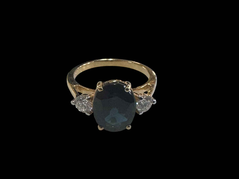 Three stone sapphire and diamond ring, the central oval sapphire 3.40 carats flanked by round brilliant cut diamonds totalling 0.37 carats, set in yellow gold, size M.