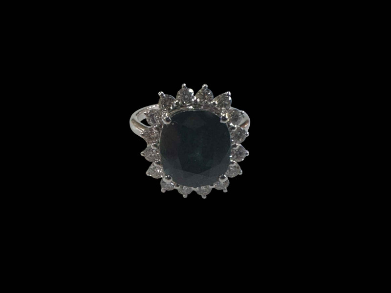 Large sapphire and diamond cluster ring, the oval central sapphire over 5 carats surrounded by sixteen brilliant cut diamonds totalling 0.71 carats set in 18 carat white gold, size N.