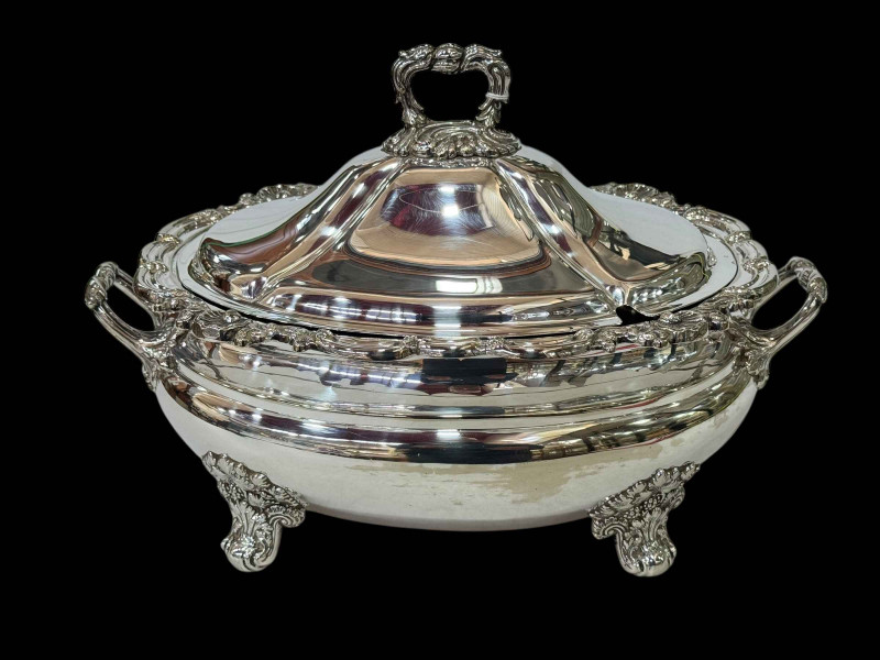 Silver plated soup tureen with scroll and shell border and on ornate feet, 34cm across.