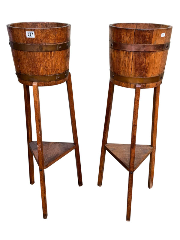 R A Lidster & Co Ltd, pair circular oak and brass bound planters on triform bases with undershelf, 92cm by 26cm diameter.