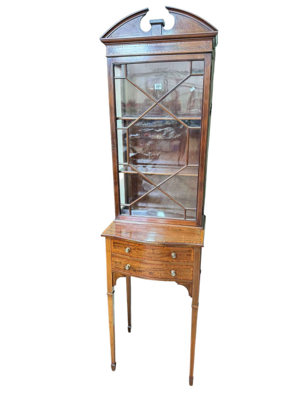 Edwardian inlaid mahogany slim cabinet, the astragal glazed top above a serpentine front base of two drawers on square tapering legs, 188cm by 51cm by 30cm.