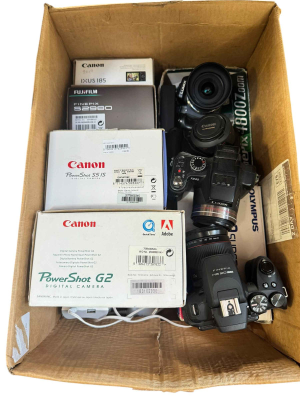 Box of digital cameras including Canon IXS 185, Panasonic G5, etc.
