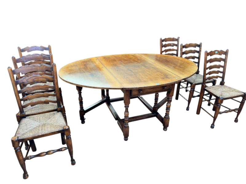Titchmarsh & Goodwin oak drop leaf dining table having two frieze drawers, 75cm by 183cm by 129.5cm (leaves elevated), together with a set of six rush seated ladder back dining chairs.