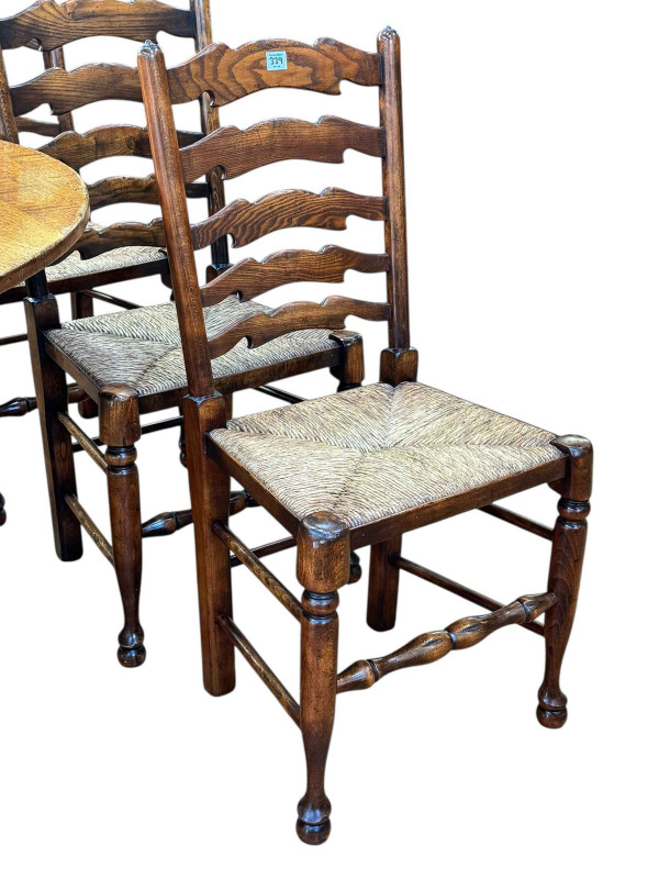 Titchmarsh & Goodwin oak drop leaf dining table having two frieze drawers, 75cm by 183cm by 129.5cm (leaves elevated), together with a set of six rush seated ladder back dining chairs.