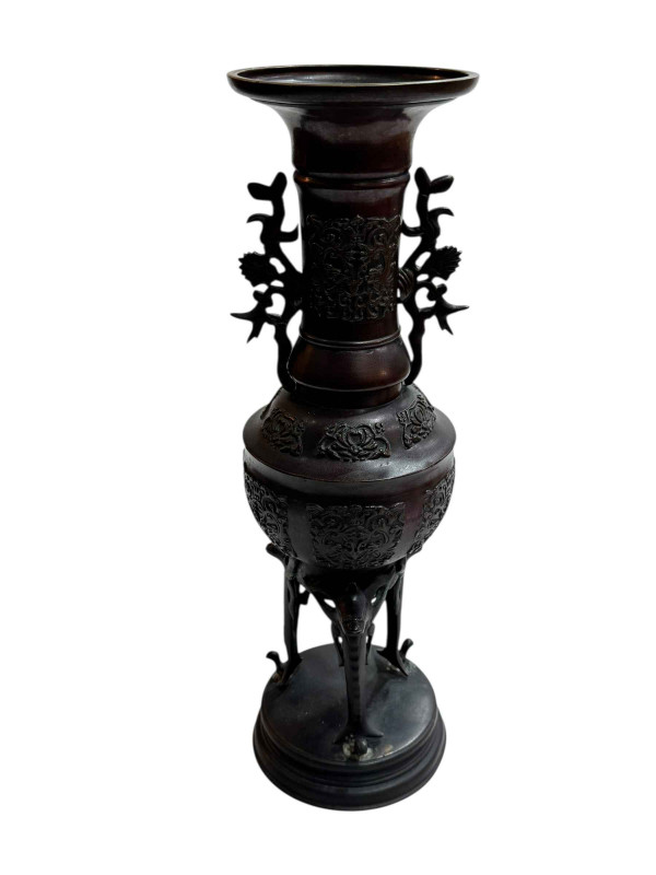 Large Japanese bronze vase with twin handles decorated in relief mythical creature and flower raised on three legs to circular base, 45.5cm.