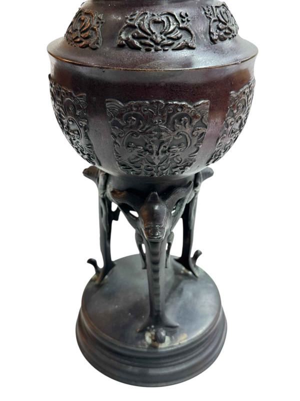 Large Japanese bronze vase with twin handles decorated in relief mythical creature and flower raised on three legs to circular base, 45.5cm.